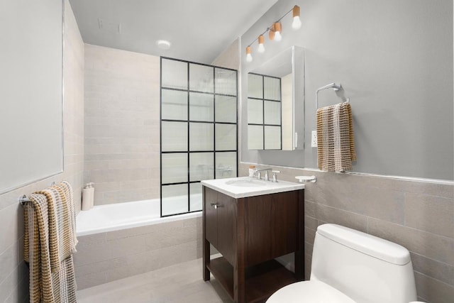 full bathroom with vanity, tiled shower / bath, tile walls, and toilet