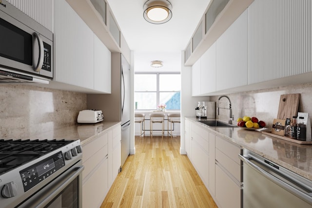 kitchen with white cabinets, decorative backsplash, sink, and stainless steel appliances