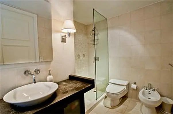 bathroom with a shower stall, tile walls, toilet, a bidet, and vanity