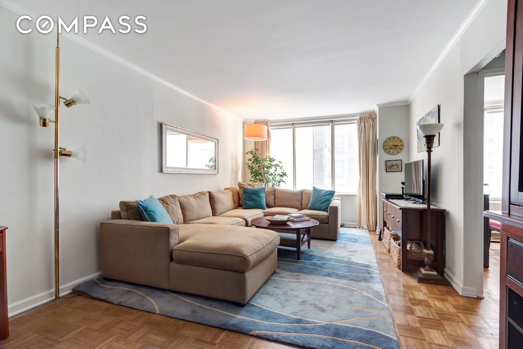 living area with crown molding and baseboards