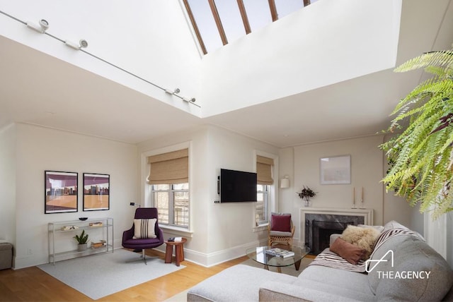 living area featuring light wood-type flooring, a high end fireplace, and baseboards