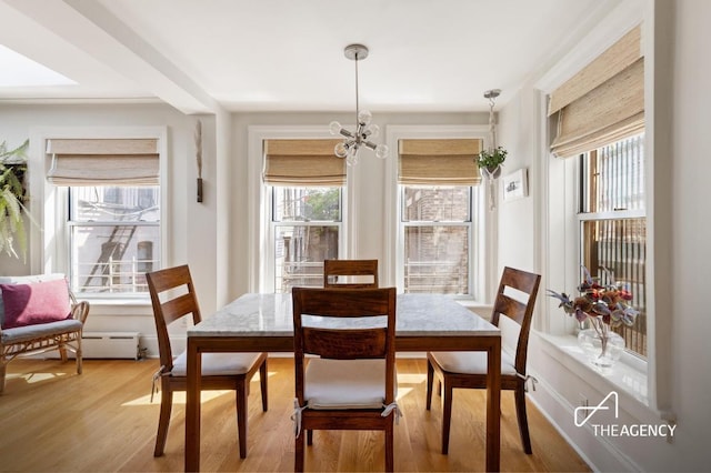 dining space with an inviting chandelier, wood finished floors, and a healthy amount of sunlight