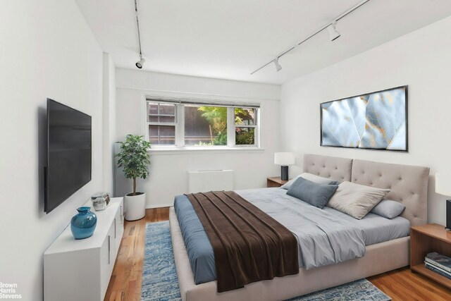 bedroom featuring track lighting and light hardwood / wood-style flooring