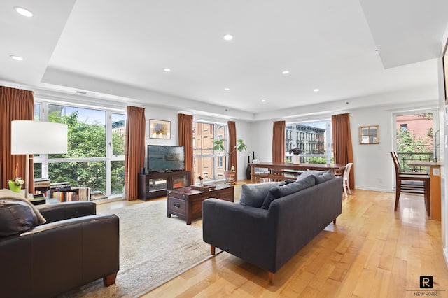 living area with baseboards, light wood-type flooring, and recessed lighting