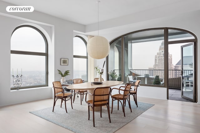 dining room featuring light wood-style floors, a view of city, and visible vents