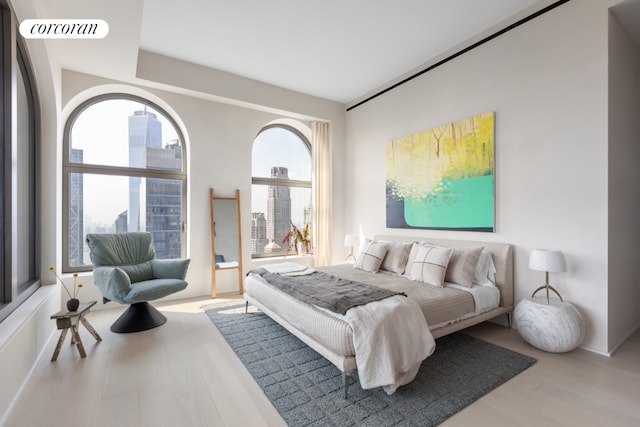 bedroom featuring multiple windows, visible vents, a city view, and wood finished floors