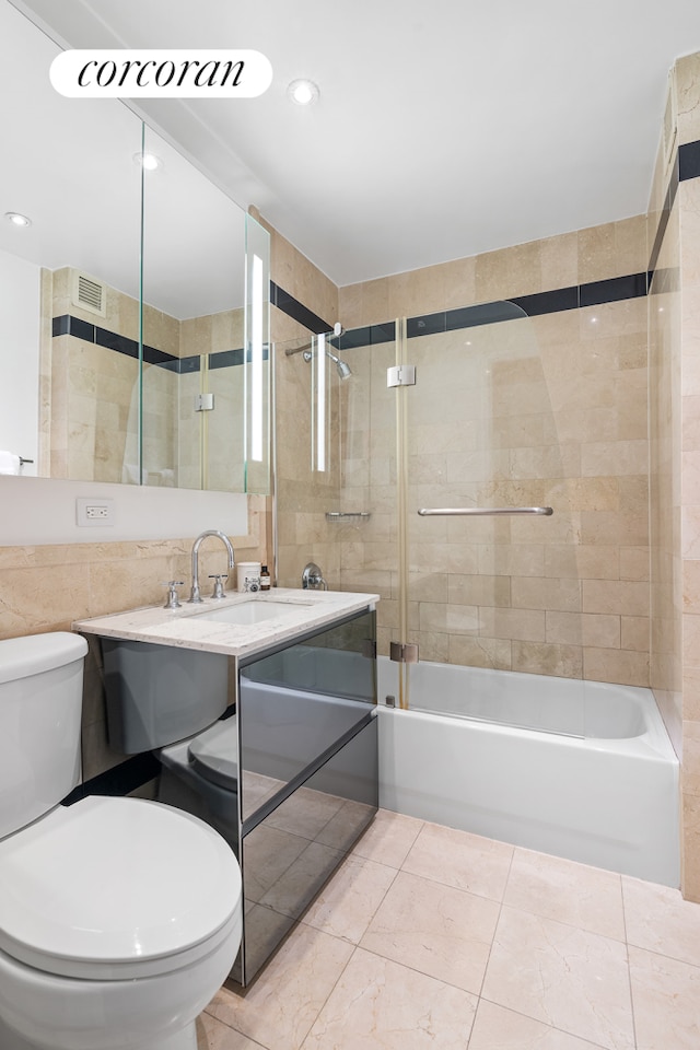 bathroom featuring vanity, washtub / shower combination, visible vents, tile walls, and toilet