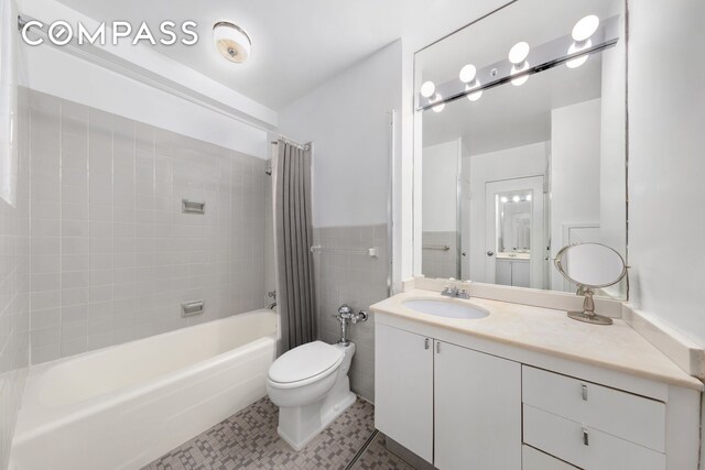 full bathroom featuring shower / tub combo with curtain, tile patterned floors, toilet, tile walls, and vanity