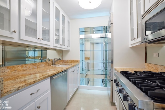 kitchen featuring white cabinets, appliances with stainless steel finishes, sink, and light stone counters