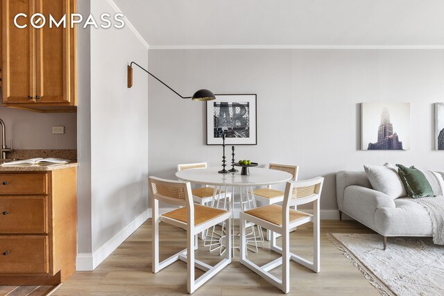 dining room featuring crown molding, baseboards, and light wood finished floors