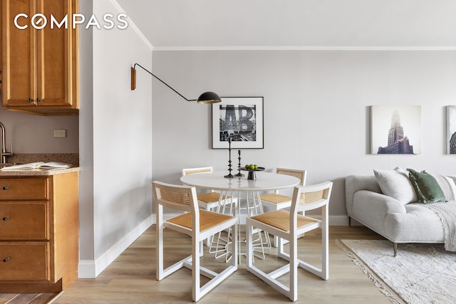 dining space with crown molding, light wood finished floors, and baseboards