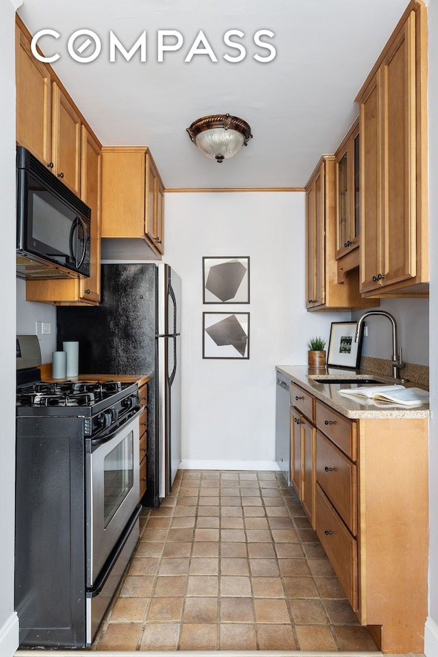 kitchen with baseboards, stainless steel appliances, brown cabinets, and a sink