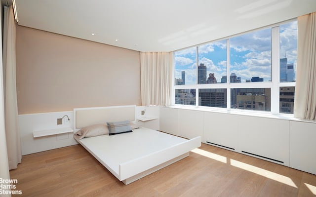 110 E 71st St Unit 19, New York City, NY 10021 - bedroom featuring a view of skyline, light wood finished floors, and multiple windows