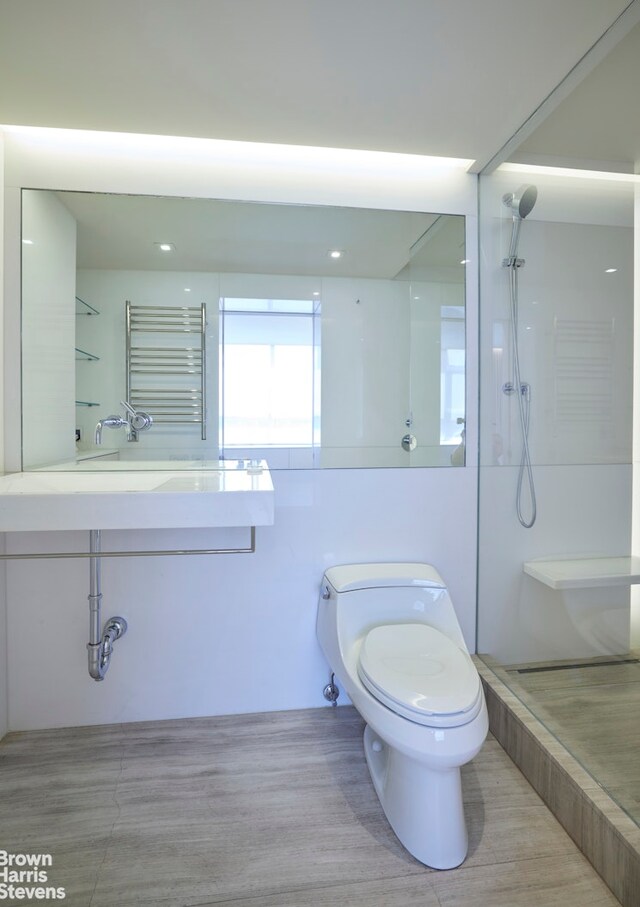 110 E 71st St Unit 19, New York City, NY 10021 - full bathroom featuring a towel warmer, a walk in shower, toilet, wood finished floors, and vanity