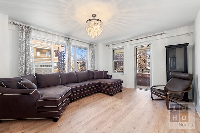 living area with light wood-type flooring, cooling unit, and a notable chandelier