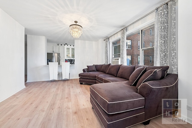 living room featuring light wood-style flooring, baseboards, and an inviting chandelier