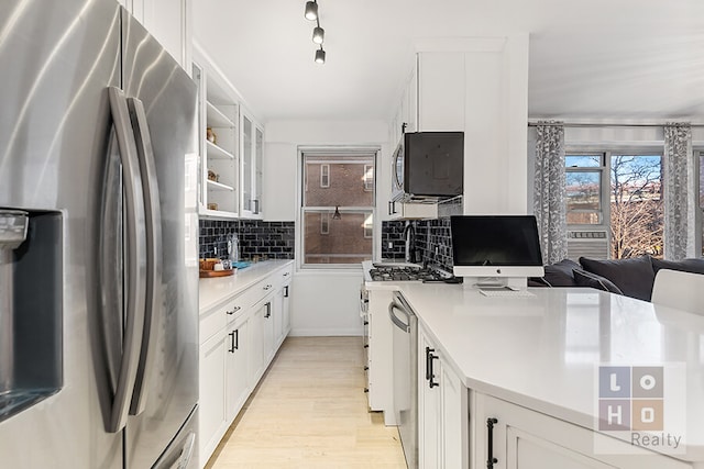 kitchen with appliances with stainless steel finishes, white cabinets, decorative backsplash, and light countertops