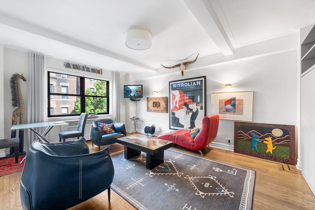 interior space with beamed ceiling, wood finished floors, and baseboards