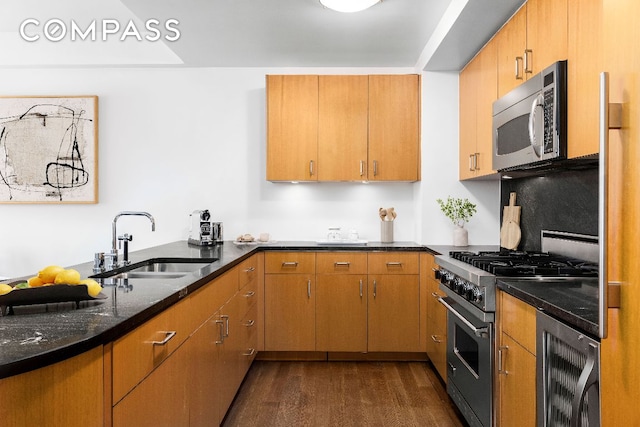 kitchen featuring sink, dark stone counters, dark hardwood / wood-style flooring, stainless steel appliances, and beverage cooler