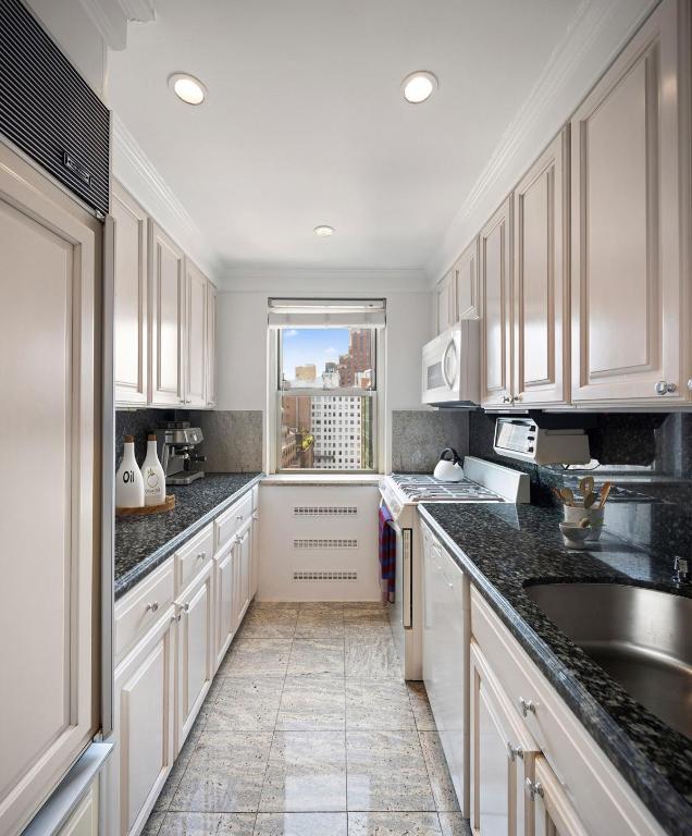 kitchen with white cabinetry, white appliances, dark stone counters, and tasteful backsplash