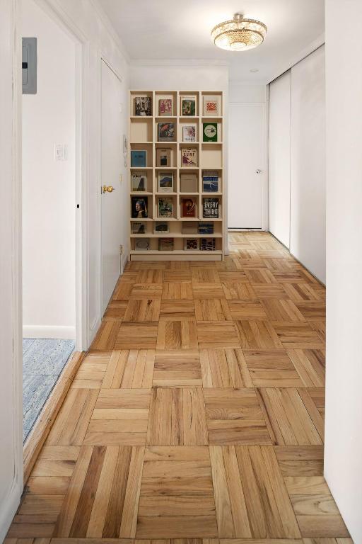 hall with light parquet floors and electric panel