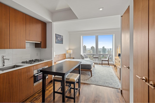 kitchen featuring stainless steel appliances, brown cabinets, a sink, and wood finished floors