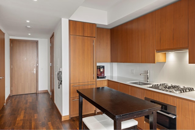 kitchen featuring modern cabinets, appliances with stainless steel finishes, brown cabinets, and a sink