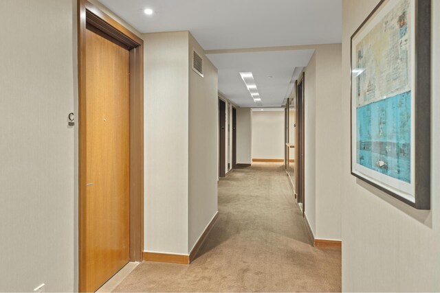 hallway with visible vents, baseboards, and carpet flooring