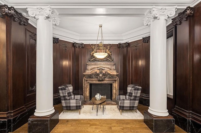 sitting room with decorative columns, a fireplace, crown molding, and wood finished floors