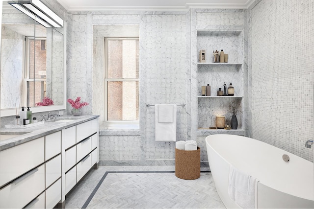 bathroom with a freestanding tub, a sink, tile walls, double vanity, and crown molding