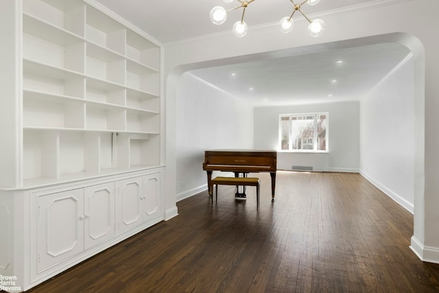 misc room featuring dark wood-type flooring, built in features, crown molding, and a chandelier