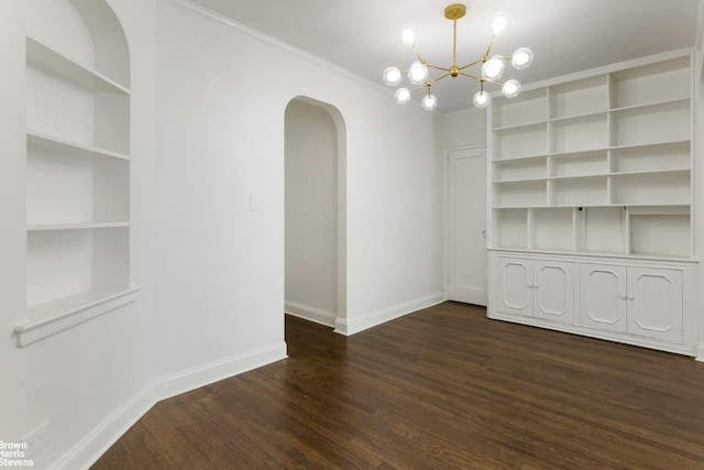 unfurnished dining area featuring dark hardwood / wood-style floors, built in features, ornamental molding, and a chandelier