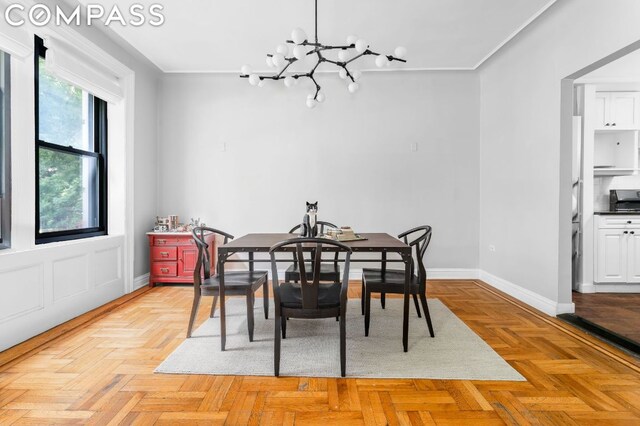 dining room featuring a notable chandelier, crown molding, and light parquet floors