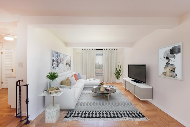 living area featuring beamed ceiling and baseboards