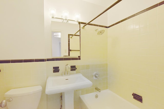 bathroom with toilet, tile walls, shower / bathing tub combination, and a sink