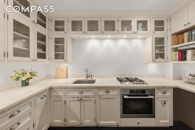 kitchen featuring a sink, open shelves, white cabinetry, appliances with stainless steel finishes, and glass insert cabinets