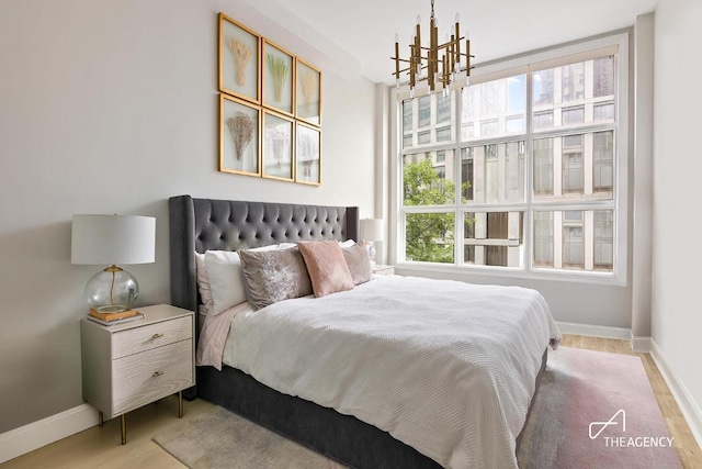 bedroom with light wood-type flooring and an inviting chandelier