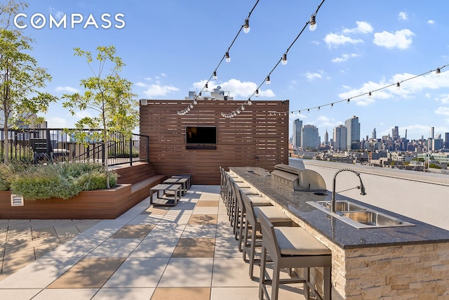 view of patio / terrace featuring a bar, a view of city, a sink, and area for grilling