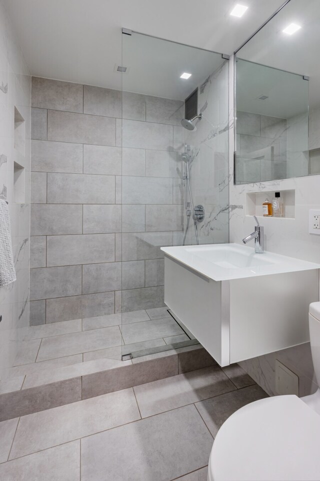 bathroom with tile patterned floors, toilet, vanity, and a tile shower