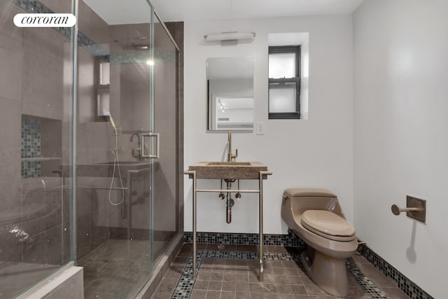 full bath with tile patterned flooring, toilet, a sink, baseboards, and a stall shower