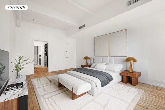 bedroom with light wood-style floors, beam ceiling, and visible vents