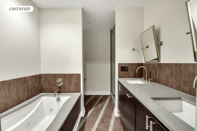 bathroom with double vanity, a sink, a jetted tub, and tile patterned floors