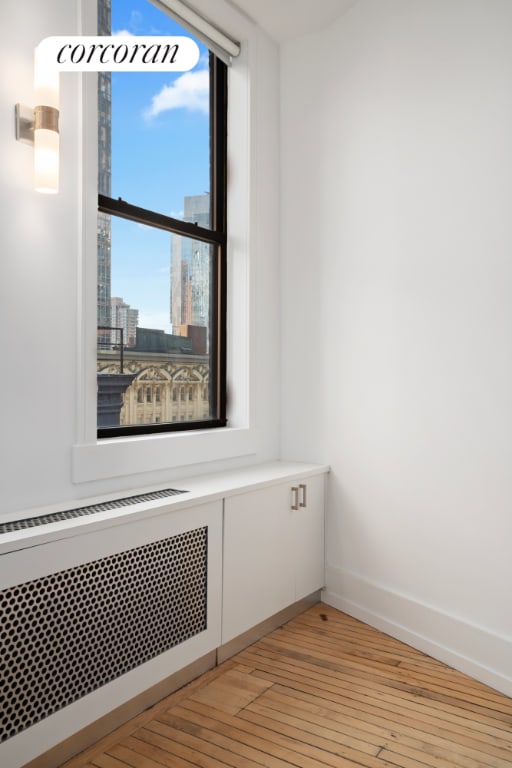 room details with radiator, a view of city, baseboards, and wood finished floors