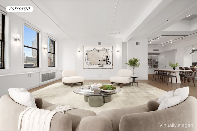 living room featuring rail lighting, radiator, visible vents, and wood finished floors