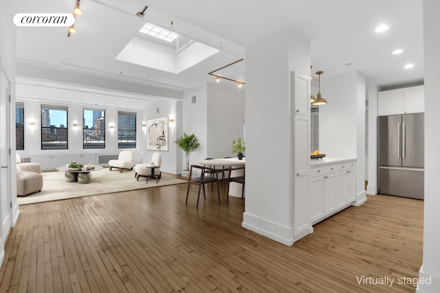 interior space with light countertops, freestanding refrigerator, white cabinetry, and light wood finished floors