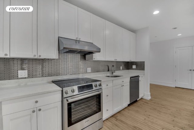 kitchen featuring white cabinets, range hood, stainless steel appliances, and a sink