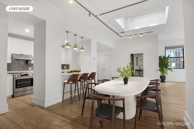 dining room featuring light wood finished floors, baseboards, visible vents, and track lighting