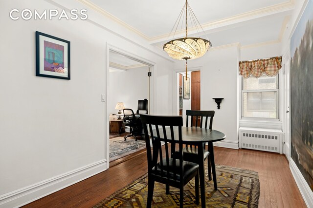 dining room with radiator, an inviting chandelier, crown molding, and hardwood / wood-style floors