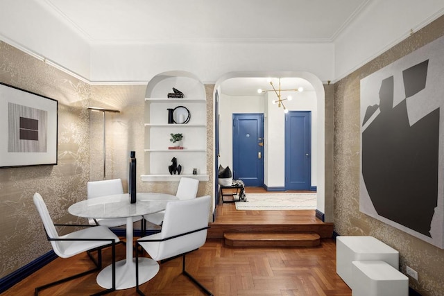 dining room featuring built in shelves, a notable chandelier, parquet floors, and ornamental molding