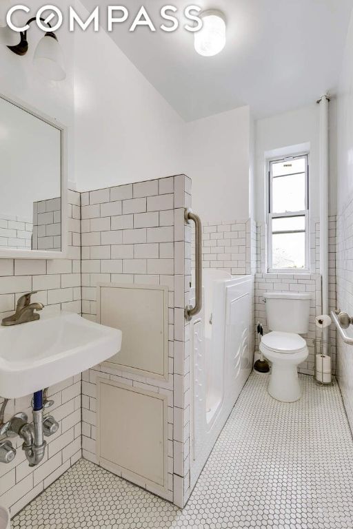 bathroom featuring tile patterned flooring, sink, tile walls, and toilet